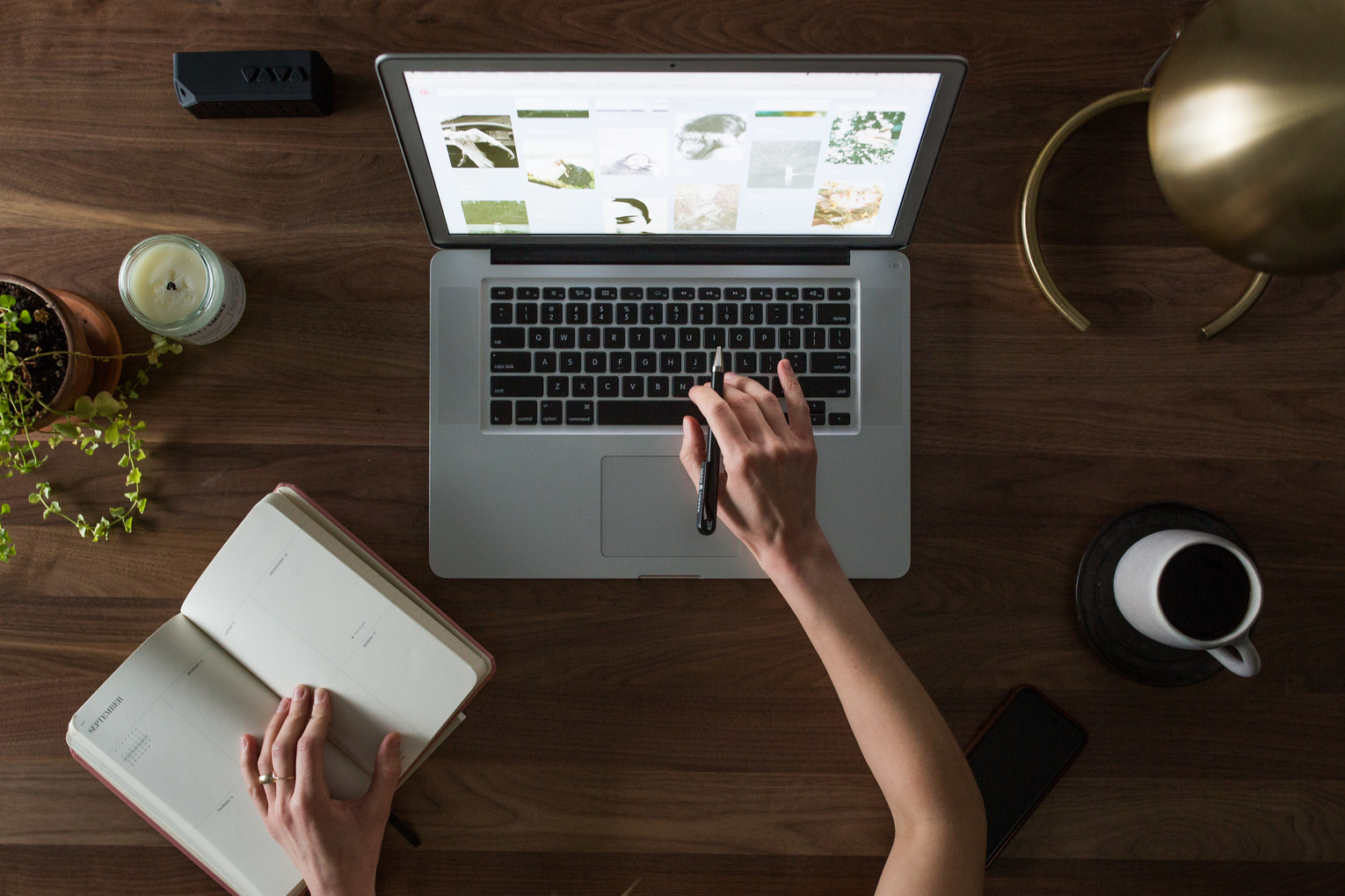 Person Using Macbook While Holding on Planner Book